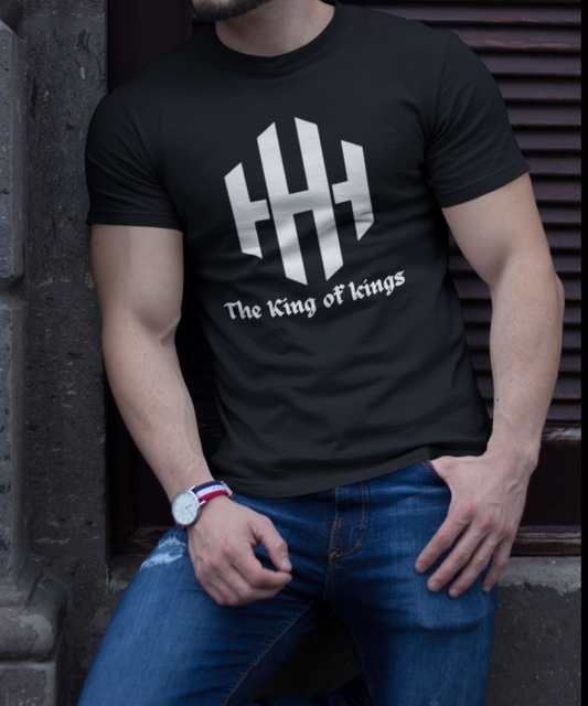 Person wearing a black t-shirt with a logo and text, sitting against a dark background.
